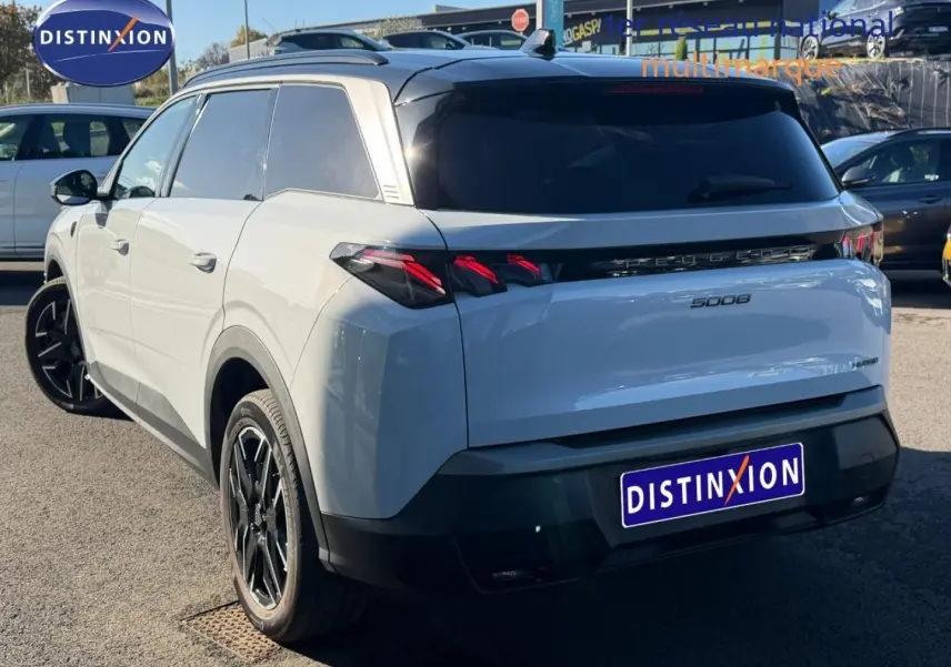 Vue 3/4 arrière droite d’un Peugeot 5008 Hybrid blanc Okénite avec feux arrière LED et jantes noires.