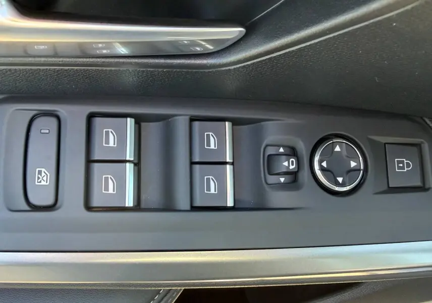 Gros plan sur les commandes de lève-vitres et réglages des rétroviseurs côté conducteur du Peugeot 5008 Hybrid blanc.