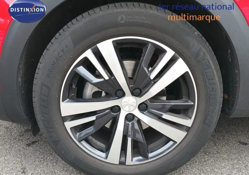 Gros plan sur la jante bi-ton en alliage du côté arrière droit d'un Peugeot 3008 rouge foncé métal.