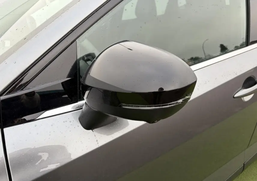 Rétroviseur côté gauche noir brillant sur Nissan Qashqai III gris foncé métallisé sous pluie légère.