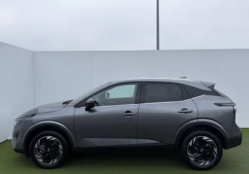 Profil côté gauche du Nissan Qashqai III 2025 en gris foncé métallisé avec jantes alliage noires et vitres teintées.