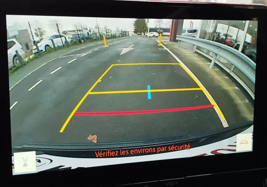 Vue caméra de recul du Toyota Corolla Cross noir intense, affichant les lignes d'aide au stationnement sur un sol asphalté.