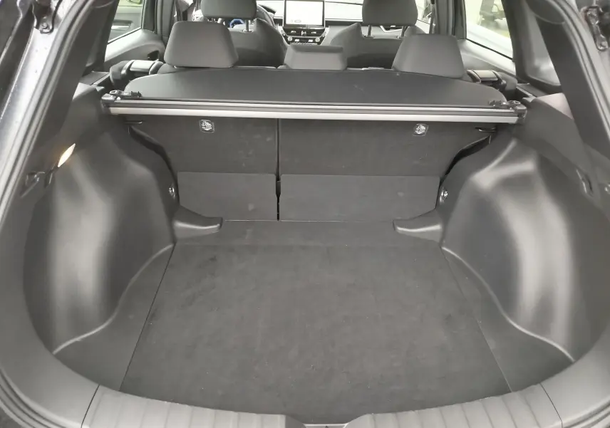 Coffre ouvert de la Toyota Corolla Cross noir intense, vue arrière montrant l'espace de chargement et la plage arrière.