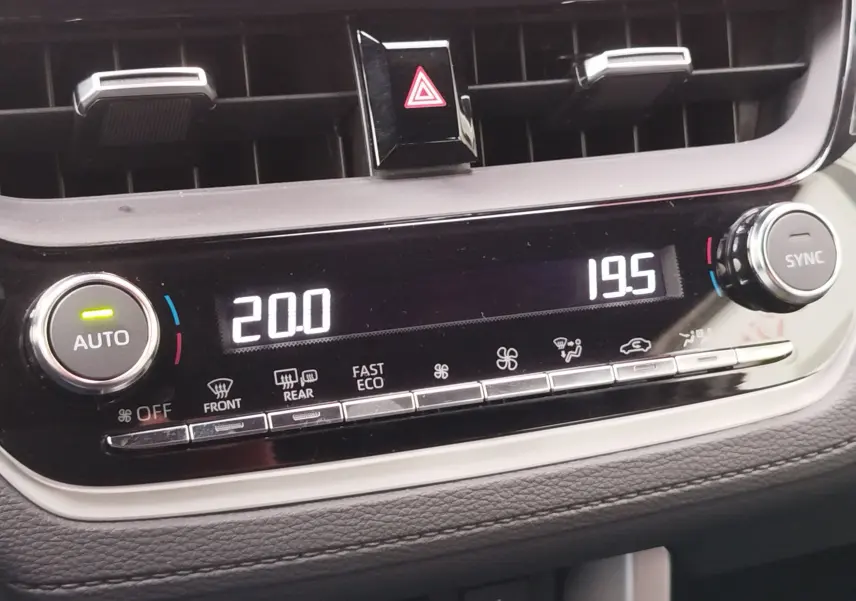 Vue rapprochée du tableau de bord de la Toyota Corolla Cross 2025, affichant la climatisation digitale avec réglages à 20 et 19,5 degrés.
