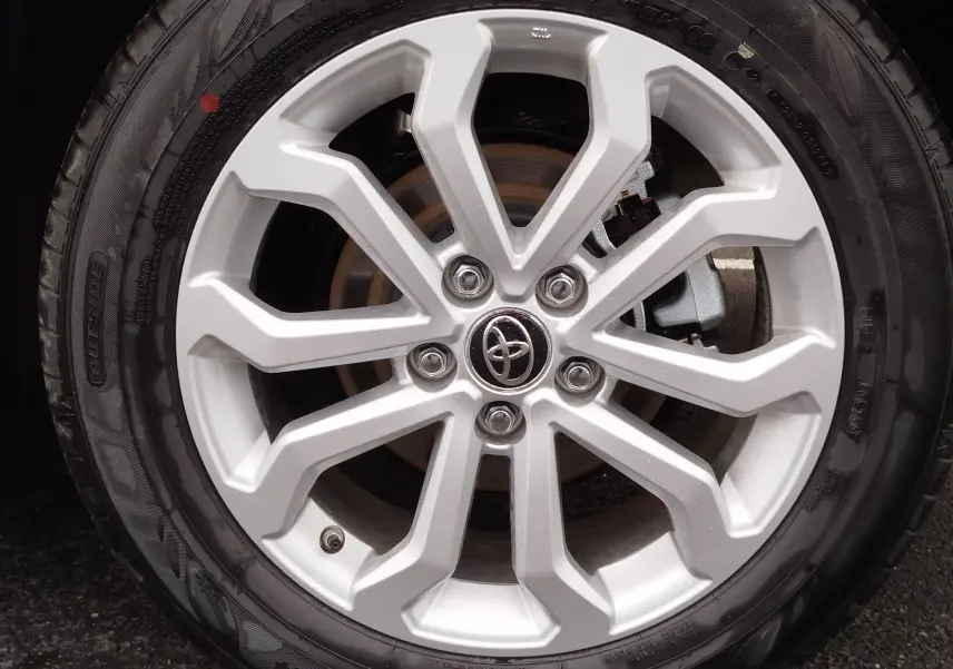 Gros plan sur la jante argentée en alliage avec logo Toyota au centre du Toyota Corolla Cross noir intense 2025.