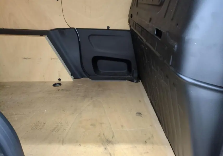 Vue intérieure de la zone de chargement du Citroën Berlingo gris clair avec plancher bois antidérapant et parois noires.