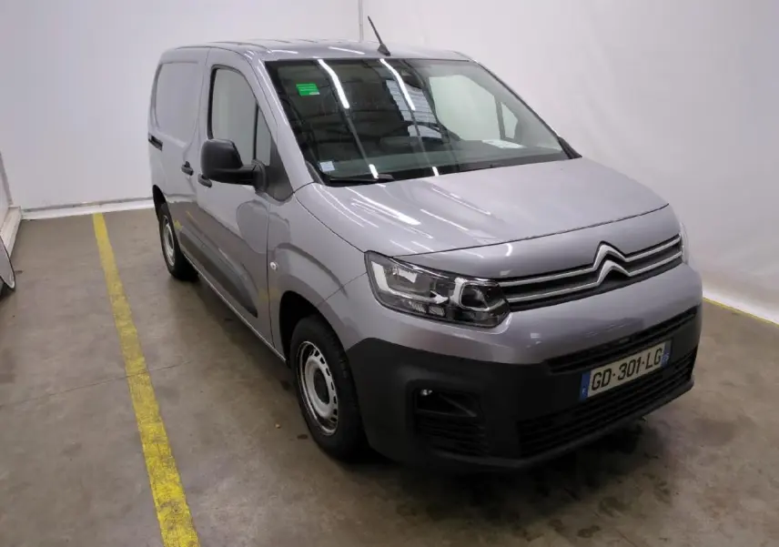 Vue 3/4 avant droit d'un Citroën Berlingo gris clair avec pare-chocs noirs et jantes tôles 15 pouces.