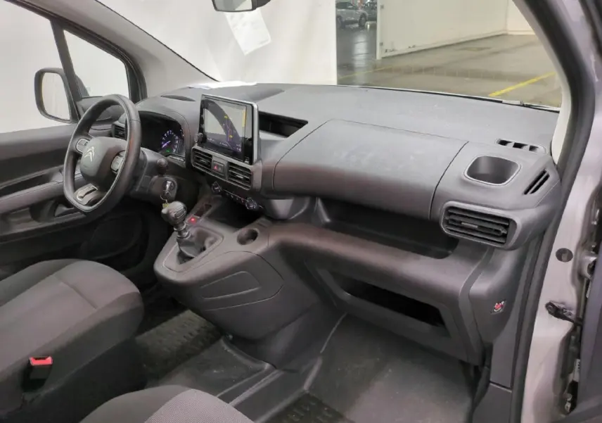 Vue intérieure côté passager du tableau de bord gris foncé du Citroën Berlingo 2021 avec écran tactile central et volant moussé.
