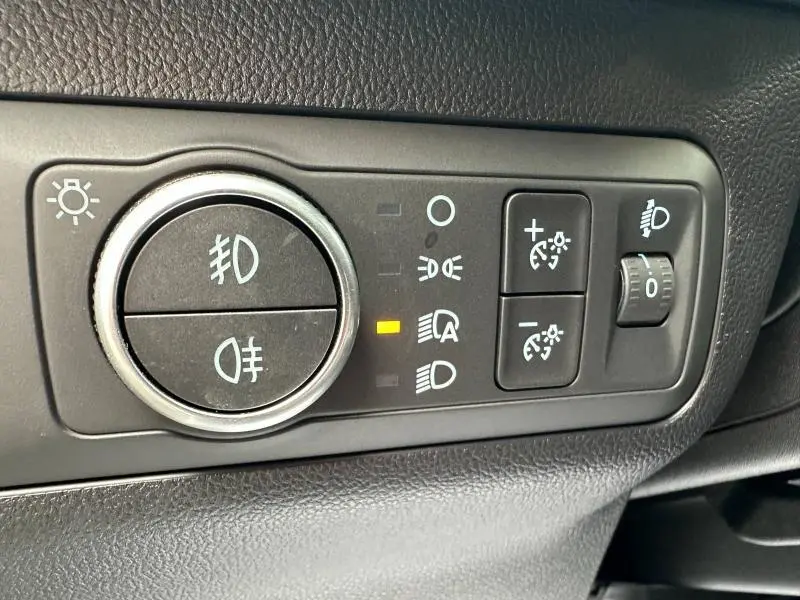 Gros plan sur les commandes d’éclairage du Ford Kuga 2024, avec réglage des phares et boutons de luminosité.