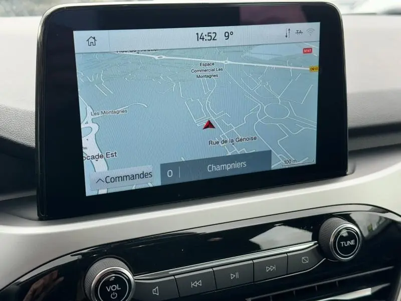 Écran tactile central du Ford Kuga 2024 affichant la navigation GPS, avec commandes audio en dessous.