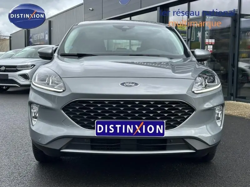 Vue frontale d'un Ford Kuga 1.5 EcoBoost 2024 gris Solar métallisé avec calandre noire et phares LED allumés.