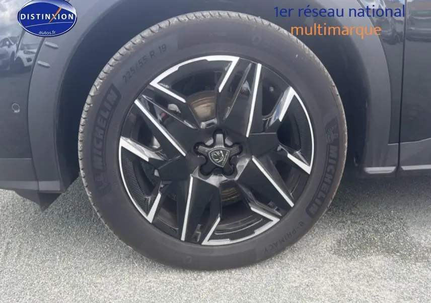 Gros plan sur la roue avant gauche noire du Peugeot 5008 Hybrid 145 allure e-dcs6 avec jante alu bicolore.