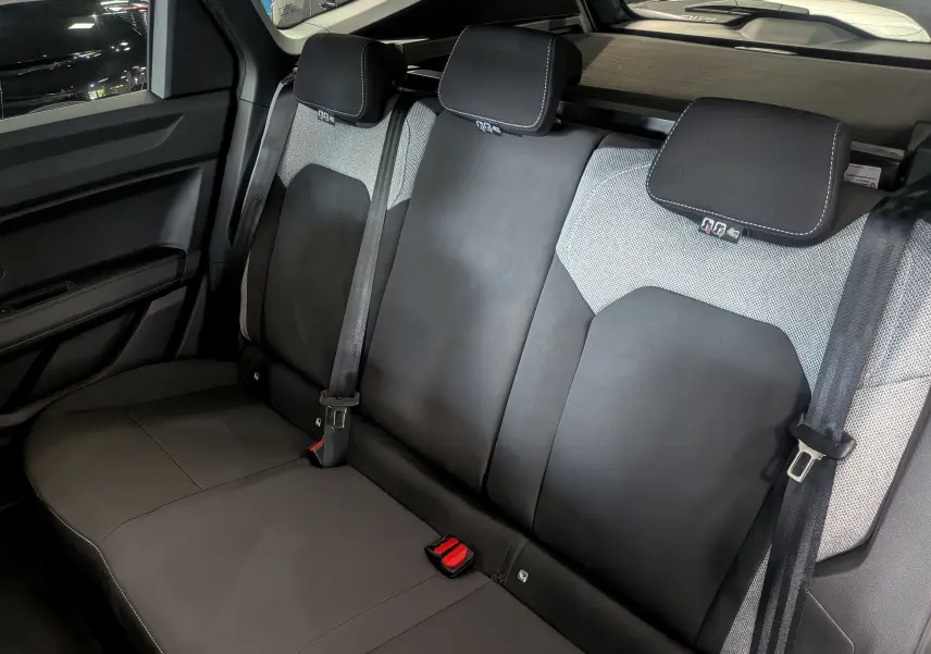 Vue intérieure sur la banquette arrière en tissu noir et gris du Dacia Bigster 2026, avec ceintures de sécurité visibles.
