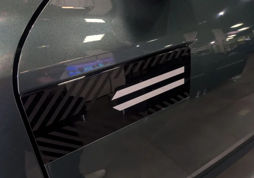 Détail du côté gauche vert cèdre du Dacia Bigster 2026 avec insert décoratif noir et blanc en motif rayé.