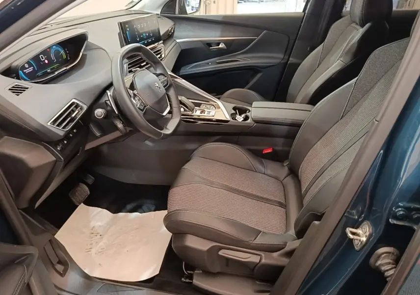 Vue intérieure côté conducteur du Peugeot 3008 bleu 2023, avec volant cuir multifonctions et tableau de bord numérique.