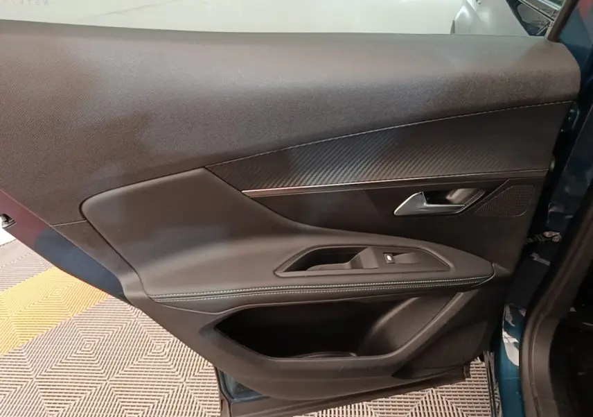 Vue intérieure côté gauche de la porte arrière bleu du Peugeot 3008 1.6 HYBRID avec garniture noire et surpiqûres.