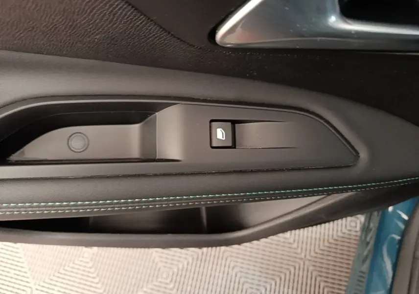 Gros plan sur la commande d’ouverture de trappe à carburant sur la porte côté gauche d’un Peugeot 3008 bleu.
