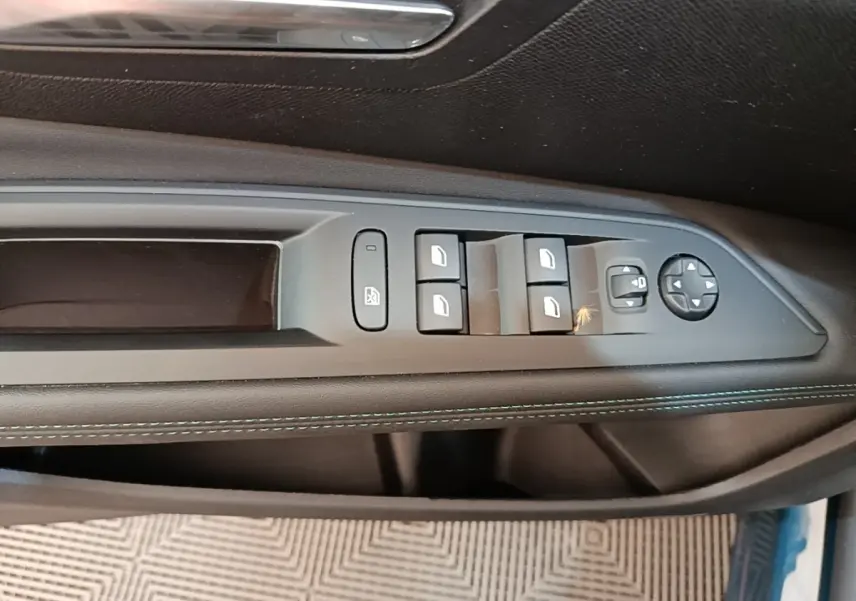 Gros plan sur la commande des vitres côté gauche en cuir noir avec surpiqûres bleues du Peugeot 3008 hybride bleu 2023.
