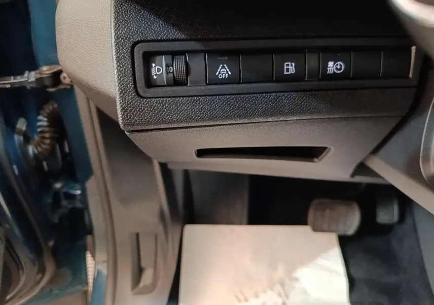 Vue intérieure côté conducteur du Peugeot 3008 bleu, montrant les commandes sous le tableau de bord et les pédales.