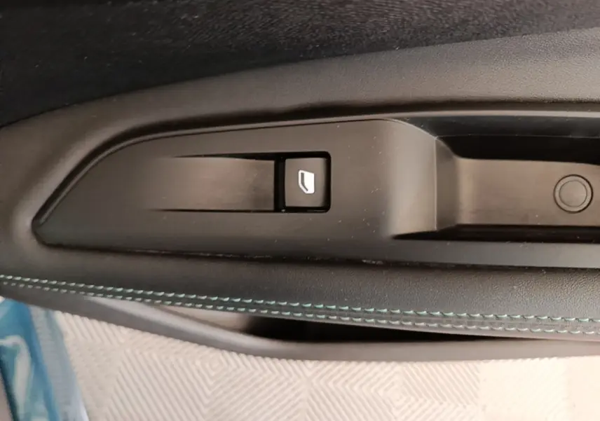 Gros plan sur le bouton de verrouillage des portes sur la portière intérieure noire avec surpiqûres bleues du Peugeot 3008 hybride.