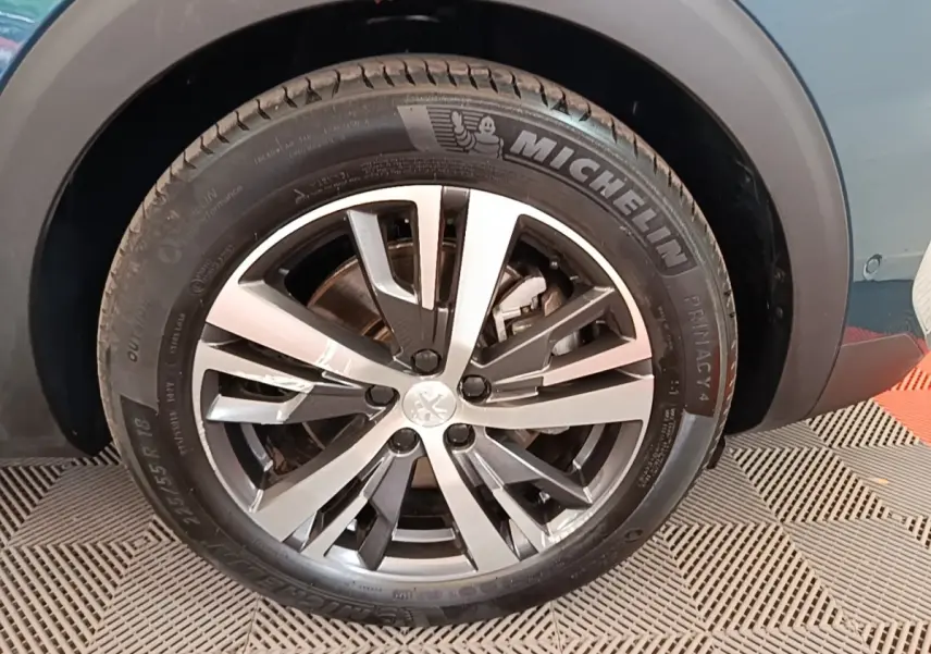 Gros plan sur la roue avant droite du Peugeot 3008 bleu, mettant en valeur la jante alliage et le pneu Michelin.