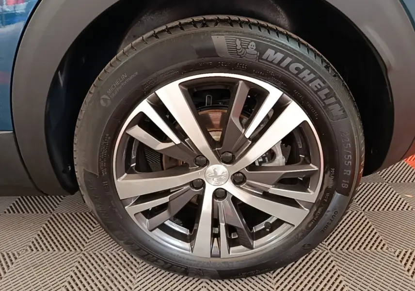 Gros plan sur la roue avant droite du Peugeot 3008 bleu, mettant en valeur la jante alliage et le pneu Michelin.