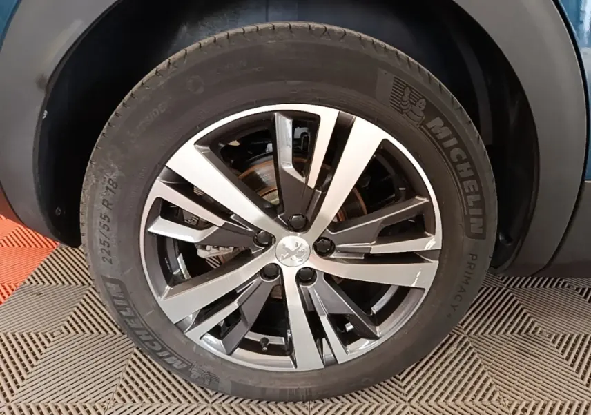 Gros plan sur la roue avant gauche du Peugeot 3008 bleu 2023, jante alliage bicolore et pneu Michelin.