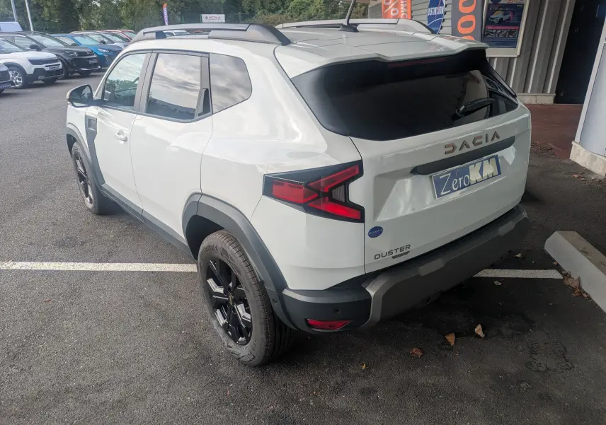 Vue 3/4 arrière droite du Dacia Duster Hybrid 155 Extreme blanc glacier avec jantes noires et vitres arrière surteintées.