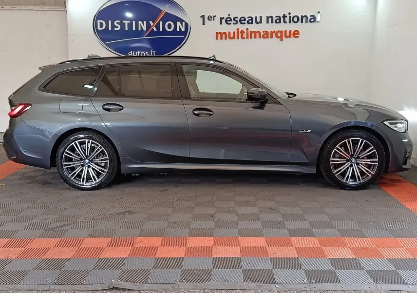 Vue de profil côté gauche d'une BMW Série 3 Touring 320e M Sport gris foncé avec jantes alliage et vitres teintées.
