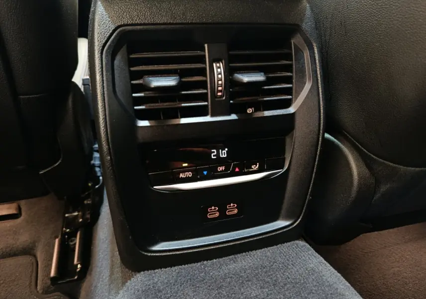 Vue rapprochée de la console centrale arrière noire avec ventilation, commandes climatisation et ports USB de la BMW Série 3 320e.