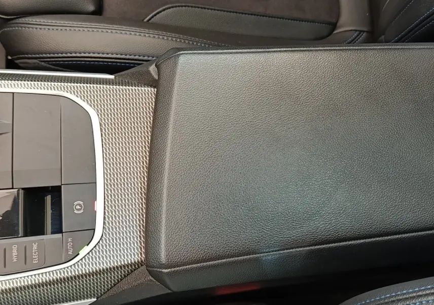 Vue rapprochée de la console centrale en cuir noir et inserts métalliques texturés de la BMW Série 3 320e M Sport hybride.