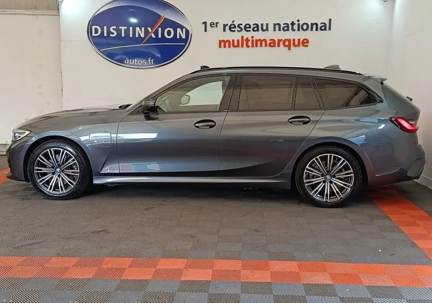 BMW Série 3 320e M Sport gris foncé vue de profil côté gauche, break hybride avec jantes sport et toit noir.