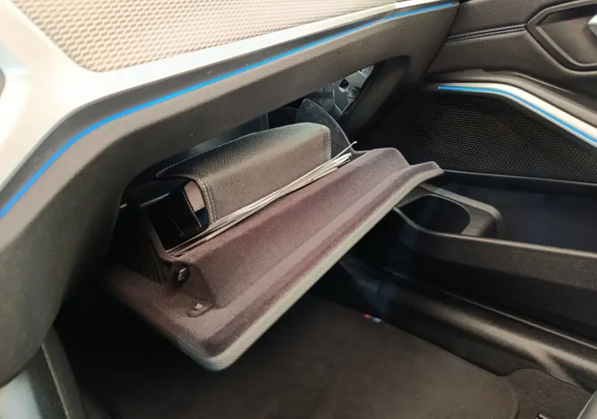 Vue intérieure côté passager de la BMW Série 3 320e M Sport 2022, boîte auto, avec boîte à gants ouverte et éclairage d’ambiance bleu.