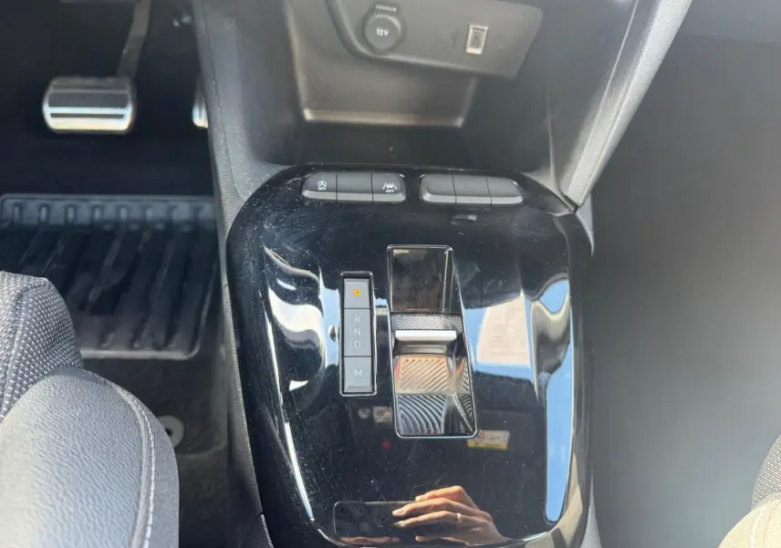 Gros plan sur la console centrale noire brillante de l’Opel Corsa 2025, montrant la commande de boîte automatique et les boutons de contrôle.