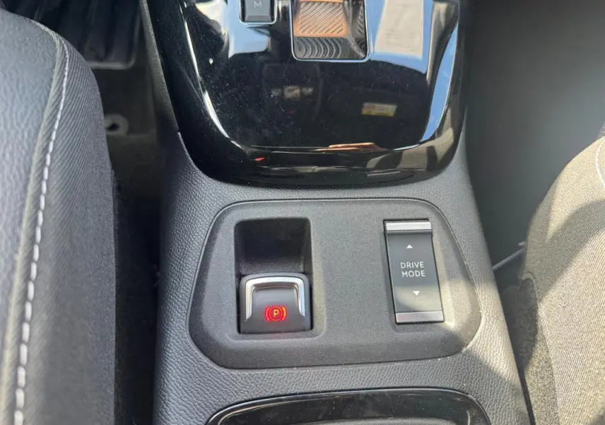 Gros plan sur la console centrale de l’Opel Corsa noire 2025, montrant le frein à main électronique et le bouton Drive Mode.