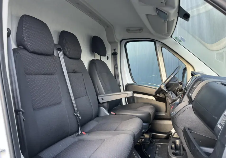 Vue intérieure côté gauche montrant les sièges avant noirs et la cabine spacieuse du fourgon Opel Movano 2024.