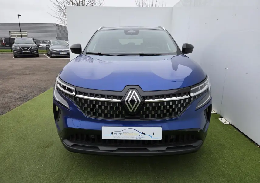 Vue de face du Renault Austral 2025 en bleu Iron avec toit noir, mettant en valeur la calandre à damier et les phares LED.