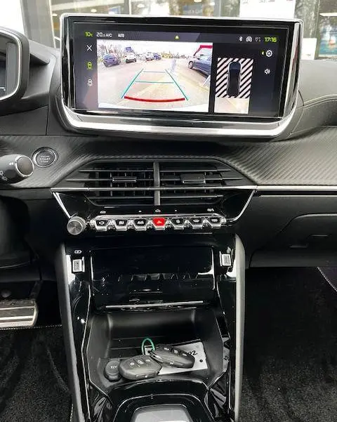 Vue intérieure du tableau de bord et console centrale du Peugeot 2008 blanc 2024, avec écran affichant la caméra de recul.