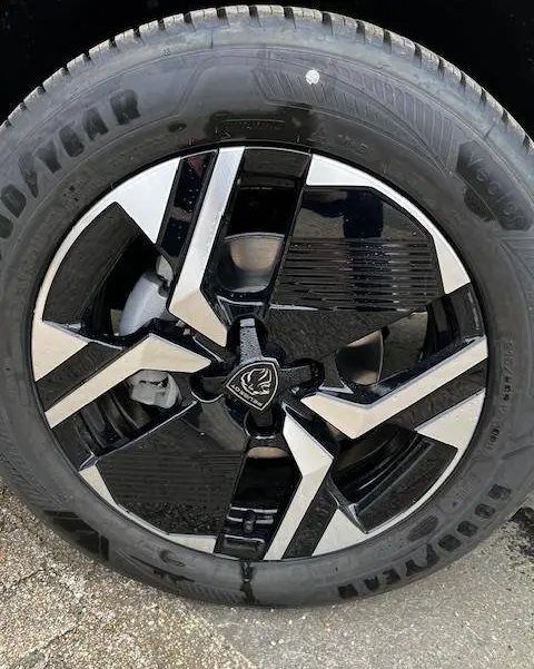 Gros plan sur la roue avant droite du Peugeot 2008 blanc 2024, jante alliage noire et argentée au design moderne.