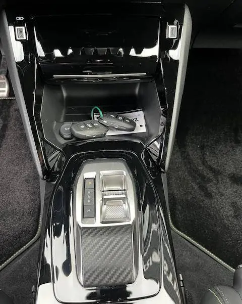 Vue plongeante sur la console centrale noire brillante du Peugeot 2008 GT 2024 avec boîte auto et clés posées.