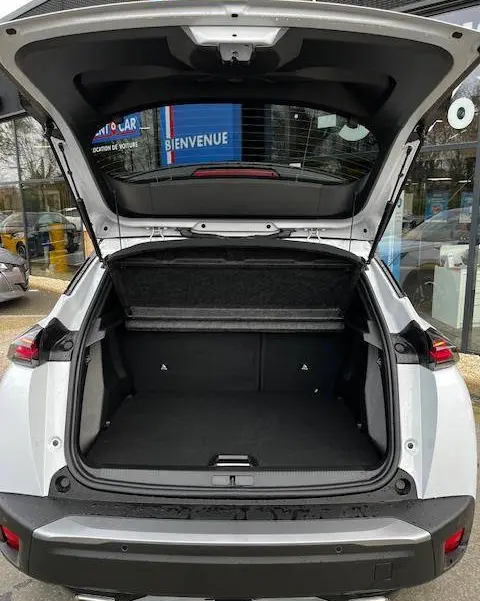 Vue arrière ouverte du coffre d’un Peugeot 2008 blanc 2024, avec hayon relevé et intérieur spacieux visible.