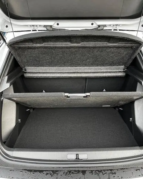 Coffre ouvert vu de dessus d'une Peugeot 2008 blanche 2024, montrant le double plancher de rangement.