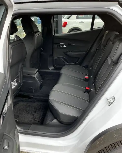 Vue intérieure arrière côté droit du Peugeot 2008 blanc 2024, sièges arrière en tissu noir avec surpiqûres grises.