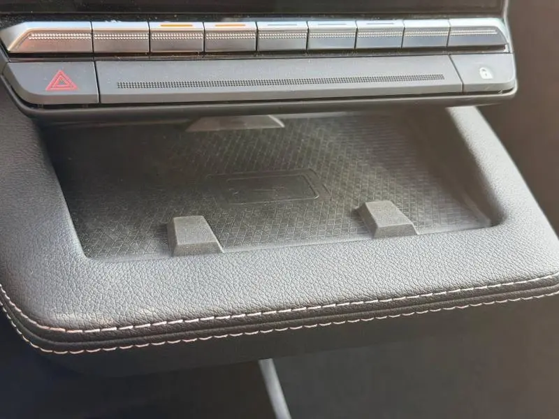 Gros plan sur le rangement central noir avec surface antidérapante et boutons de commande au-dessus dans un Renault Scenic gris Schiste 2025.