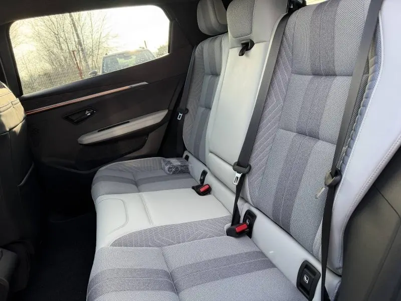 Vue côté droit des sièges arrière gris clair et tissu recyclé du Renault Scenic E-Tech Electric 2025 avec ceintures de sécurité visibles.