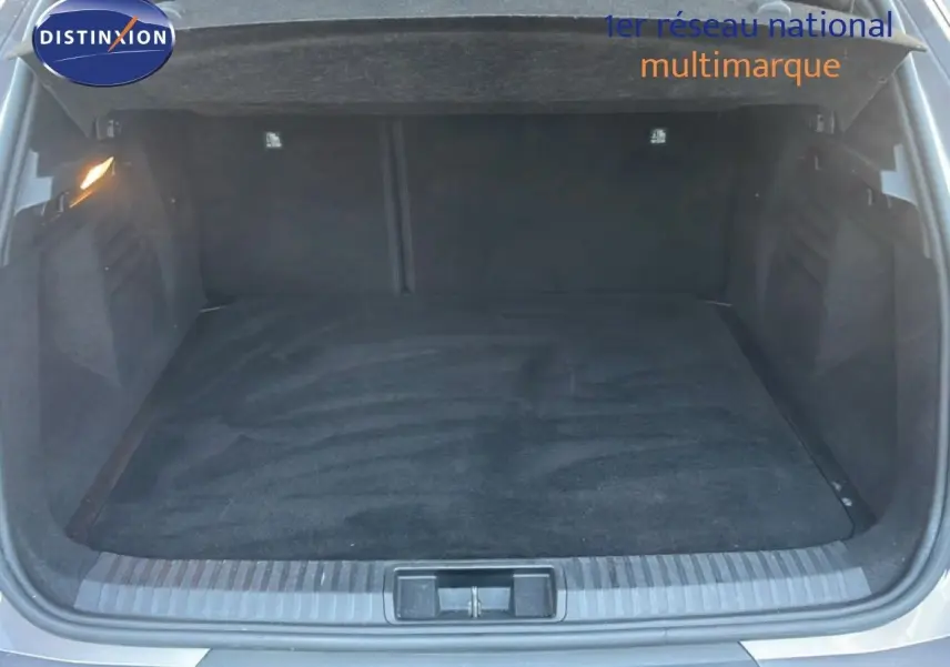 Coffre ouvert d'une Renault Symbioz gris cassiopée métal, vue arrière montrant l'espace de chargement vide et éclairé.