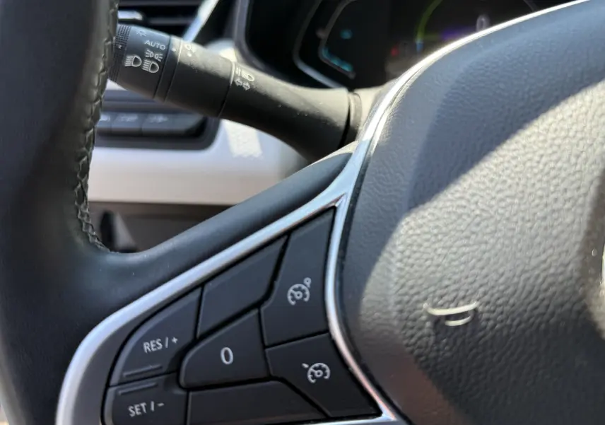 Gros plan sur la partie gauche du volant gris de la Renault Clio V 1.6 E-Tech Hybrid 2022 avec commandes de régulateur de vitesse.