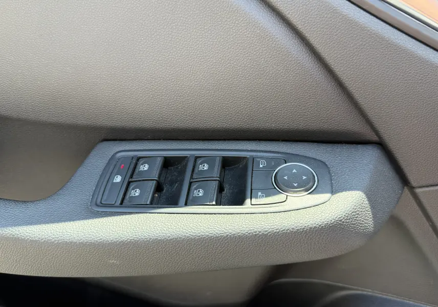 Gros plan sur les commandes des vitres électriques et réglages des rétroviseurs côté gauche d’une Renault Clio V gris 2022.