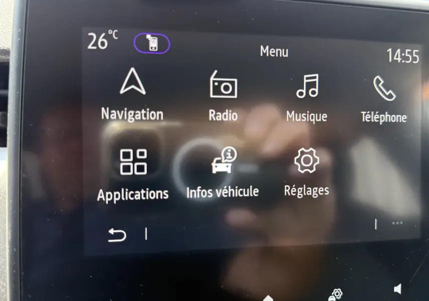 Écran tactile central de la Renault Clio V gris, affichant le menu principal avec navigation, radio et réglages.