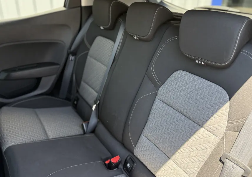 Vue intérieure des sièges arrière de la Renault Clio V gris, avec tissu texturé et ceintures de sécurité visibles.